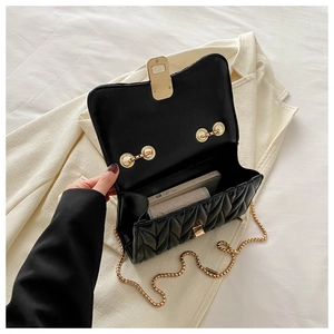 Detail view of open quilted bag with gold hardware showing interior capacity and lining