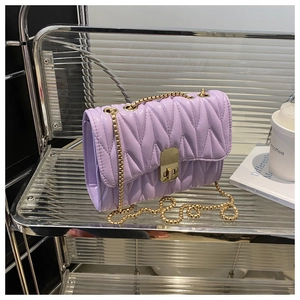 Detail view of light purple quilted handbag with gold chain and metal twist lock