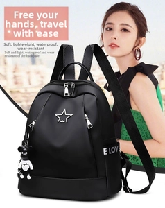 Detail of waterproof black nylon backpack with silver star logo and teddy bear charm