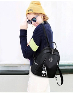 Detail of black oxford backpack featuring star logo, love strap, and bear keychain