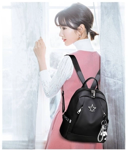 Detail of black oxford fabric backpack with star logo and cute white bear keychain