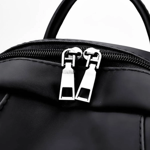 Minimalist black oxford cloth backpack featuring dual metal zippers with H-shaped pulls
