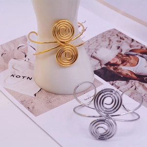 Detailed view of spiral knot bracelets in gold and silver plating on a prop stand