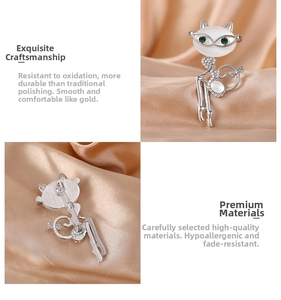 Macro view of silver cat brooch with opal head and green rhinestone eyes on satin