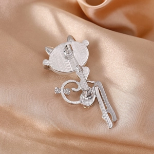 Elegant silver kitten rhinestone brooch with brushed metal finish on silk background