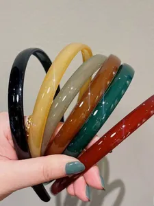 Détail de six serre-têtes fins gelée colorés avec dents antidérapantes tenus à la main