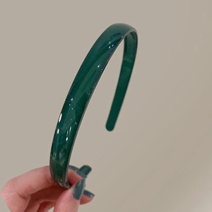 Détail d'un serre-tête fin vert foncé brillant avec une finition en résine polie