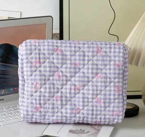 Detail of purple checkered quilted cosmetic bag with pink bow pattern and metal zipper