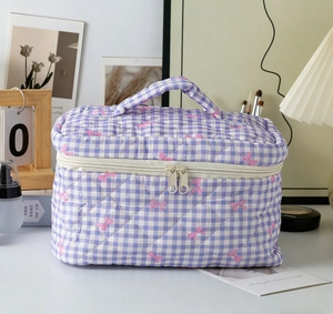 Detail of purple gingham quilted makeup bag featuring pink bows and double zipper