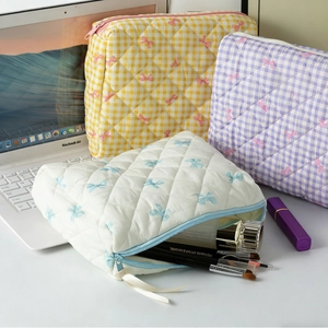 Set of three quilted bow print cosmetic bags in yellow, purple, and white colors