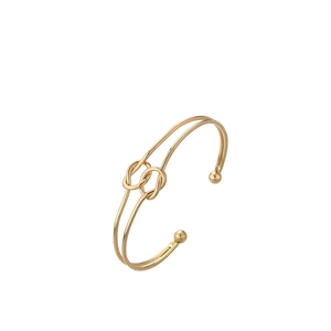 Detail of a polished gold knotted open bangle featuring parallel bands and bead ends