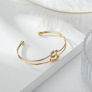 Detailed view of a gold knot open bangle featuring double wire design and ball ends