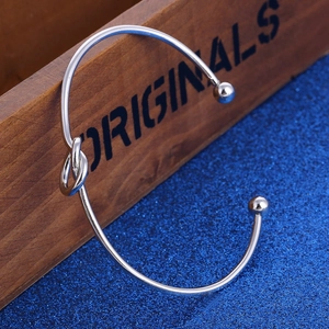 Bracelet jonc ouvert argenté avec nœud poli et embouts sphériques sur boîte en bois