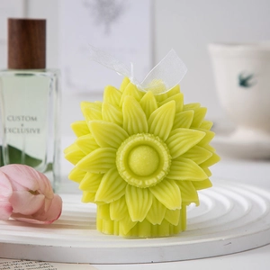 Detail of sunflower shaped candle in lime green with ribbon on a decorative tray
