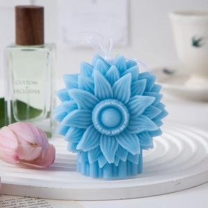 Detail of blue sunflower scented candle with intricate petal textures on a white tray