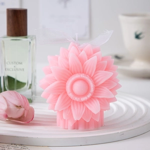 Close-up of pink sunflower scented candle with white ribbon on elegant display tray