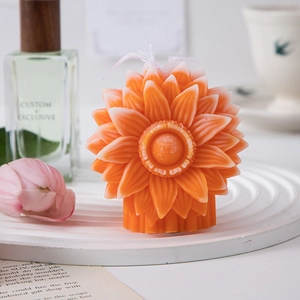 Detail of an orange flower-shaped scented candle on a decorative white tray
