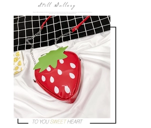 Detail of red strawberry shaped crossbody bag with glossy patent leather and silver chain