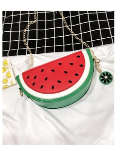 Detail shot of a watermelon-shaped crossbody bag with gold chain and green flower zipper