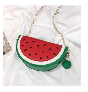 Detail of watermelon shaped semi-circle crossbody bag with golden chain and black seed print