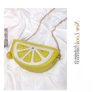 Detail of half-circle lemon crossbody bag with gold chain and flower charm