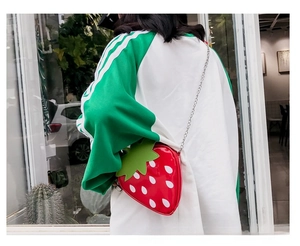 Close-up of strawberry-shaped crossbody bag featuring red patent leather and leaf detail