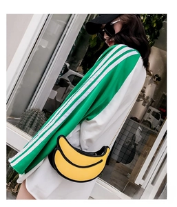 Detailed view of banana-shaped crossbody bag with gold chain strap worn by a model