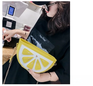 Detail of lemon shaped crossbody bag featuring vibrant yellow fruit slice design with chain