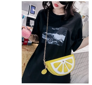 Detail shot of a yellow lemon crossbody bag with gold chain strap on a model