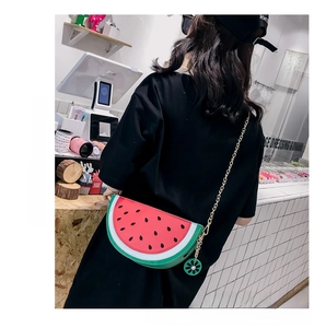 Detail of creative watermelon slice shaped crossbody bag with gold chain and floral charm