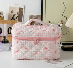 Detail of pink plaid quilted makeup bag with bow embroidery and dual zippers