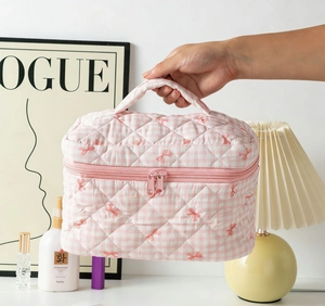 Detail of pink plaid quilted makeup bag with bow patterns and durable metal double zippers