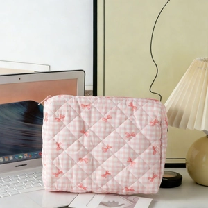 Quilted pink checkered makeup bag with red bow prints on a cozy white desk setup