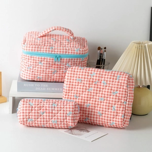 Detailed set of three orange checkered quilted pouches with blue bow patterns