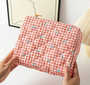 Detail of red gingham quilted bag with blue bow patterns held by a model