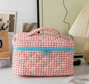 Detail view of quilted red gingham bag with blue bow prints and zip closure