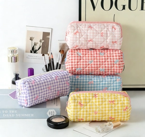 Detailed stack of quilted cotton vanity bags featuring bow embroidery and check patterns