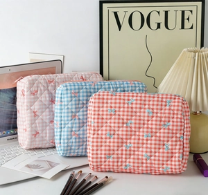 Close-up of quilted floral bow embroidery cosmetic bags in pink blue and orange plaid