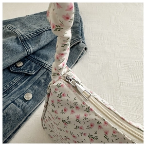 Detail of floral tote bag featuring tulip prints and a ruffled handle near a denim jacket