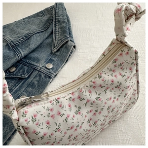 Close-up of floral tote bag showing the zipper closure and knotted strap detail