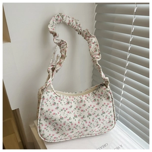 Detailed view of floral canvas shoulder bag with ruffled strap and silver zipper closure