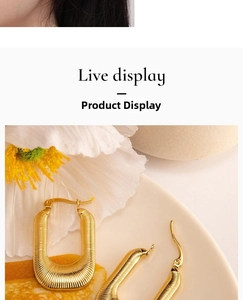 Close-up of golden U-shaped earrings featuring a fine textured surface on a white tray