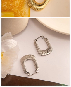 Close-up of silver and gold irregular U-shaped earrings with vertical pleated texture