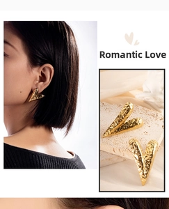 Detail of heart-shaped gold earrings with hammered texture on stone background and model