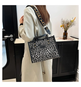 Detail of leopard print tote bag with wide jacquard strap and top handle on a model