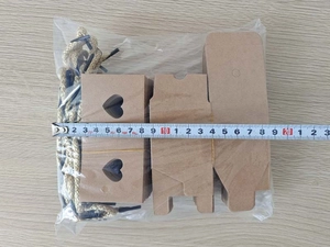 Flat lay of DIY kraft paper gift box kit with heart cutout and gold cords and measuring tape