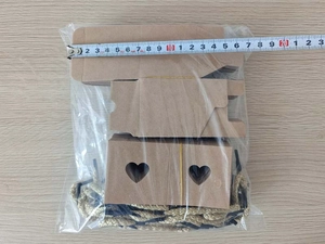 Flat lay of DIY kraft paper gift boxes with heart cutouts and jute twine, measures 20cm