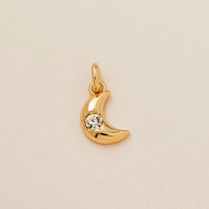 Macro shot of 18k gold plated moon pendant with sunburst engraving and zircon stone