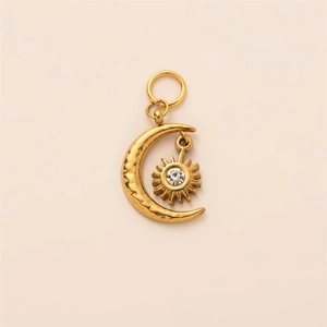 Close-up of hammered gold moon and sun pendant with a sparkling zircon stone