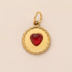 Detailed view of a gold-plated scalloped heart pendant with a deep red gemstone center